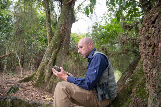 istock Man researches field guide book for bird identification. Man in birding activity. 2177694572