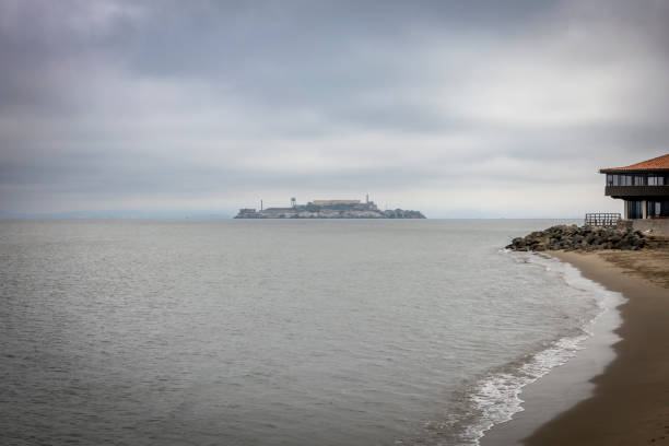 exterior view of Penitentiary of Alcatraz island in San Francisco with a plane flying in the background