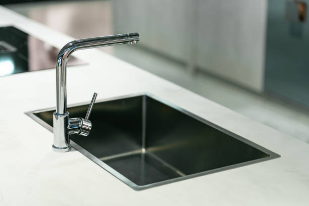 A sleek sink and faucet set into the countertop of a beautiful kitchen in a luxury villa. The space is filled with warm natural daylight, highlighting the elegant design and creating a bright, inviting atmosphere perfect for everyday use.