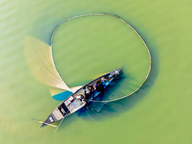 A breathtaking aerial view of a tranquil lake, with a small fishing boat dotting the horizon against a backdrop of rolling hills.