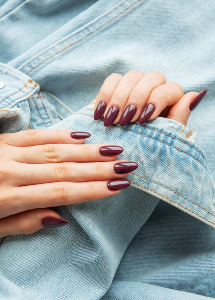 istock Elegant hands with polished burgundy nails resting on a denim jacket sleeve showcasing a stylish look in natural light 2177707902
