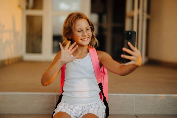 istock Smiling elementary school girl with backpack taking a selfie 2177710670