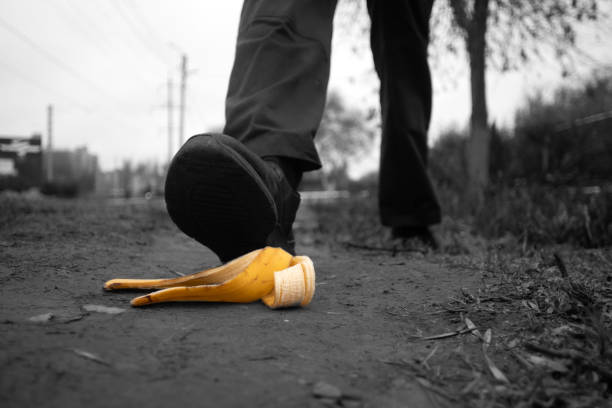 Businessman stepping on banana peel on the sidewalk.