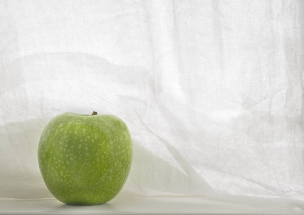 Light background with green apple with spots with stem, in horizontal format