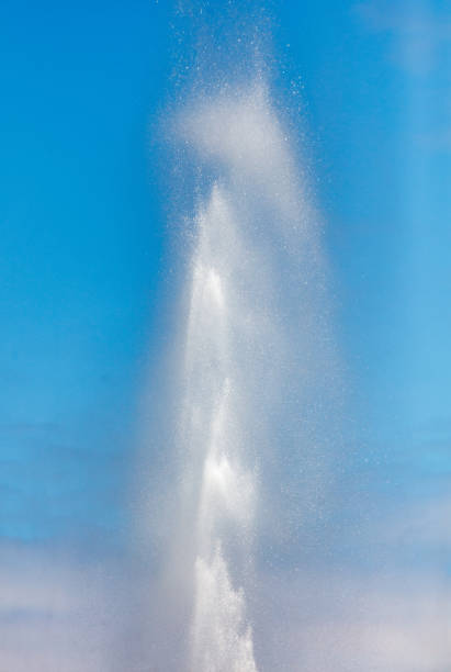 Water splashes from a fountain against a blue sky.