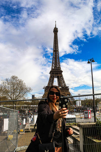 Image of a woman taking a selfie in front of the famous Eiffel Tower in Paris