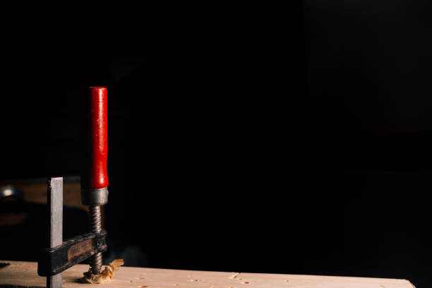 Wood clamp with red handle and dark background.