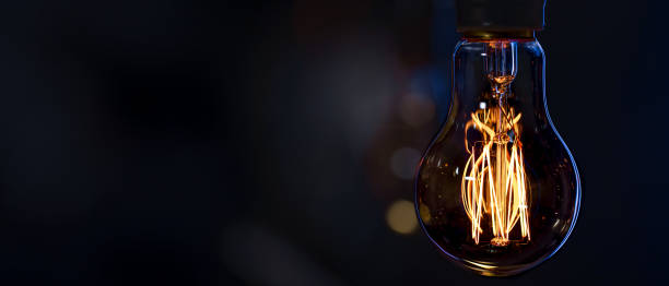 istock A burning lamp hangs in the dark on a blurred background. Space for text. 2177720895
