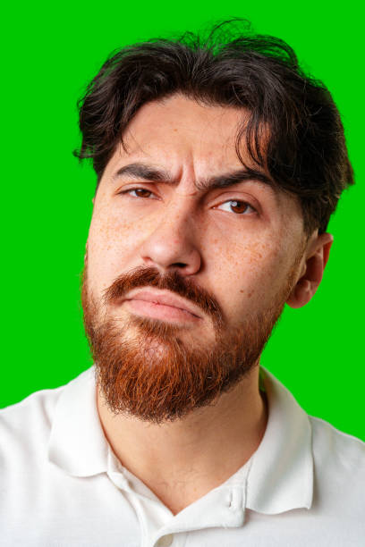 A young man with a beard showing a serious expression against a vibrant green background