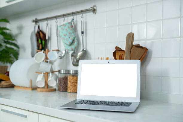 istock Mockup of laptop computer with empty screen sugar, spices in glass jars eggs, vegetable,tomato and a whisk on the kitchen on white table. Flat lay. Concept of food preparation, on background. 2177723272