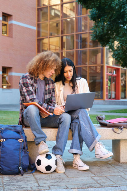 istock Two students collaborating on laptop outdoors with soccer ball 2177727554