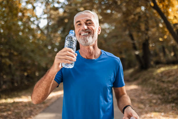 istock Active mature man exercises in public park hydrating 2177728275