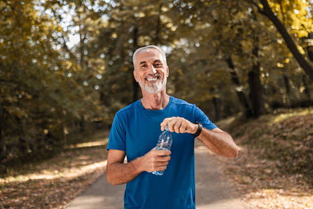istock Active mature man exercises in public park hydrating 2177728292
