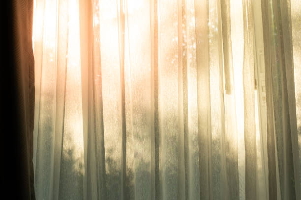 Soft light on curtains window. There was morning light through the window in room, looking at the view of the mountains and trees as the sun rose.