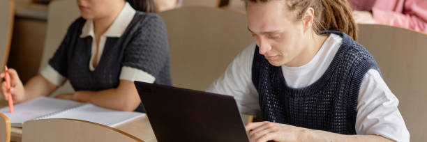 istock Young Male Student Using Laptop suring Lecture at College 2177729730