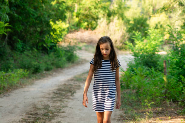 Cute girl in dress walking in nature during summer day
