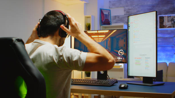 istock Back view of man with headphones playing shooter game 2177740196