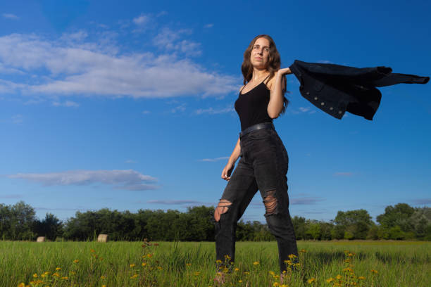 Beautiful young hungarian woman swinging her jacket in a field on a summer day