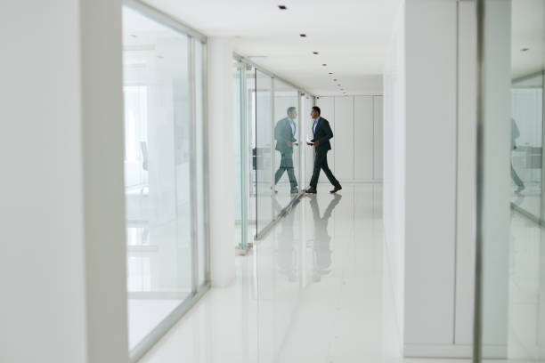 istock The man is entering the office with coffee and documents, walking through the corridor lined with glass walls. 2177742824
