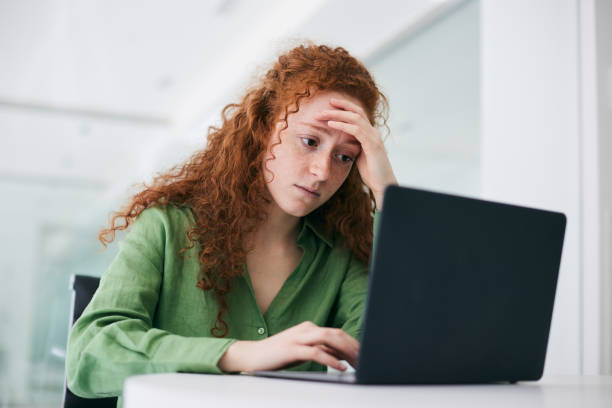 istock The redheaded student concentrates on her laptop while studying in the library. 2177743159