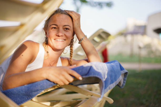 Happy blonde woman relaxing on a deckchair at the swimming pool