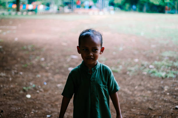 A young child standing in an open field, surrounded by greenery. Ideal for themes of childhood, nature, and outdoor exploration.