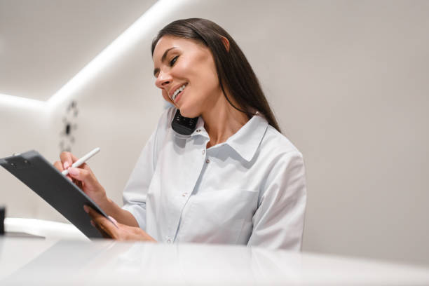 istock Caucasian female practitioner nurse reception specialist in working at reception desk while answering phone calls and scheduling appointments in medical clinic. Hospital concept. 2177780539