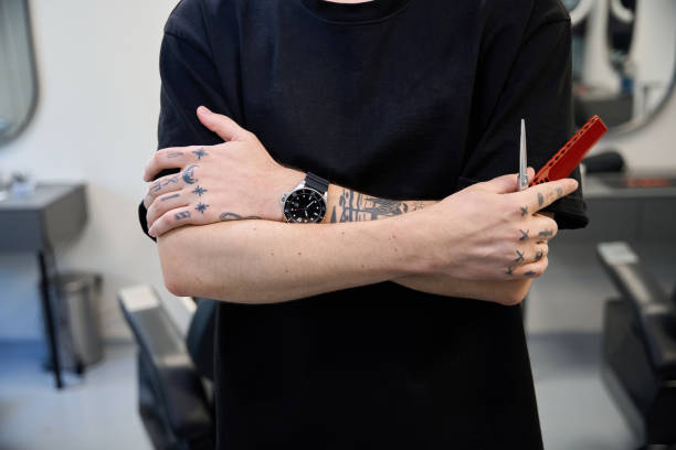 Close up photo of professional stylist holding comb and scissors, worker at barber shop