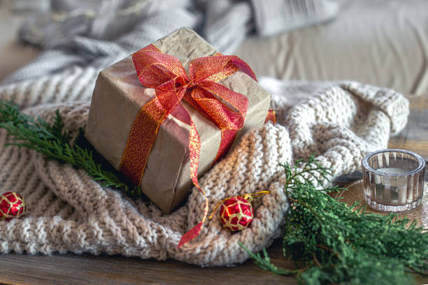 Christmas composition with a festive gift. Christmas concept. High quality photo. Christmas gift with candle. On a wooden table. Knitted sweater. Christmas tree branches.