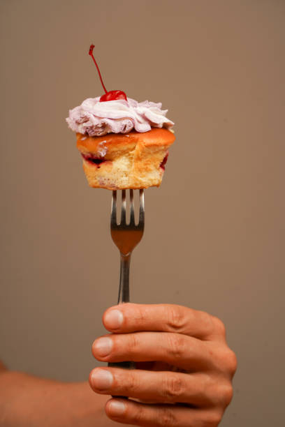 istock Cupcake decoration. Cherry on top. Cupcake. Cupcake on fork. Eating. Tasty baking cupcakes, cake or muffin with pink cream icing, frosting. Bakery. Confectionery. 2177796379