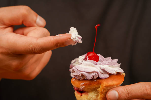 Eating. Eating cupcake with a finger. Cupcake decoration. Cherry on top. Cupcake. Birthday cupcake with cherry on top. Happy Birthday. Bakery. Confectionery