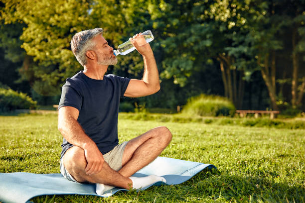 A relaxed man is enjoying practicing mindfulness in nature while carrying a water bottle with him