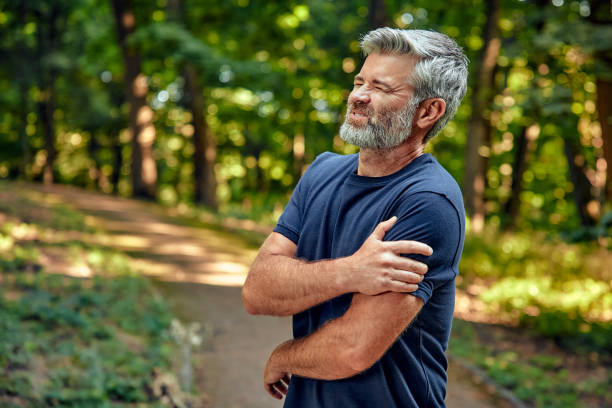 istock A man in a forest is grasping his shoulder, showing discomfort and concern for himself 2177802122
