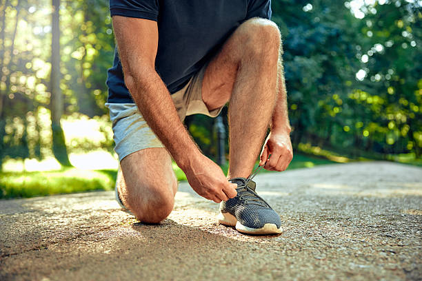 istock A Runner is Carefully Tying Their Shoelaces While Holding a Water Bottle on a Scenic Track Path 2177804351