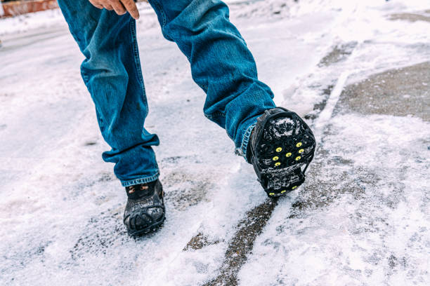 istock Workplace Safety: Snow removal worker wearing anti-slip spikes on his work boots for work in icy, slippery conditions 2177806835