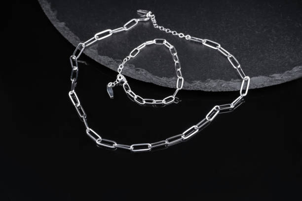 istock two chains hang from a ceramic dish. metal chain and bracelet on black background close-up. minimalist jewelry chains made of silver. 2177808280