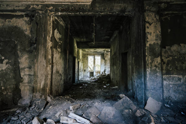 istock Abandoned corridor in dilapidated building with crumbling walls and debris scattered across the floor. Light from broken windows contrasts with dark, eerie interior, creating a sense of decay and desolation 2177809334