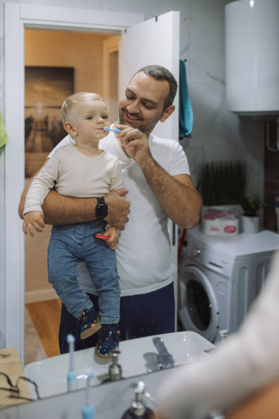 istock Young father brushing his son's teeth at bathroom 2177813743