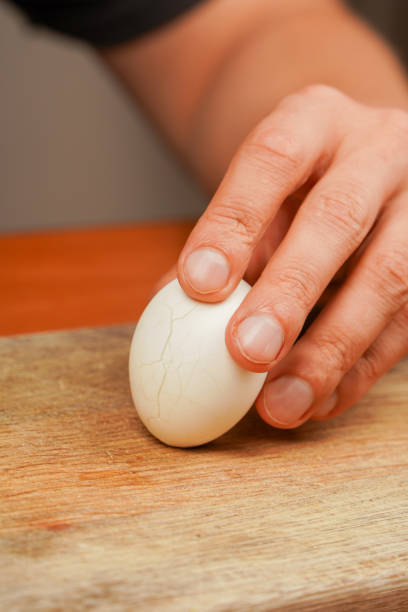 istock Man holding chicken egg over wooden board. Boiled egg. Cleaning egg from shelling, close up. Healthy food. Protein. Sportsmen's food. Preparing food. Vertical photo. Vegetarian. 2177814473