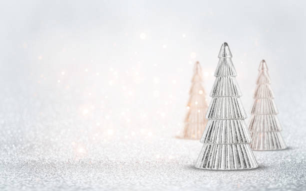 Silver Christmas tree ornaments on bright, shiny glitter background with bokeh light. Festive winter holiday decor and ornament.