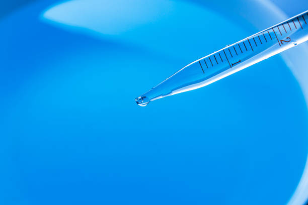 Macro blue science experiment,Close up view macro shot of gel with different sized bubbles comes out from lab dropper into petri dish on blue background