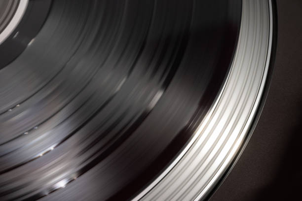 A close-up shot of a vinyl record in motion on a turntable, capturing the motion blur as the record spins. The image highlights the smooth movement and circular grooves of the vinyl, evoking the tactile nature of analog sound.