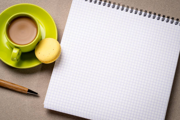 blank spiral notebook with grid paper, flat lay with coffee on textured art paper