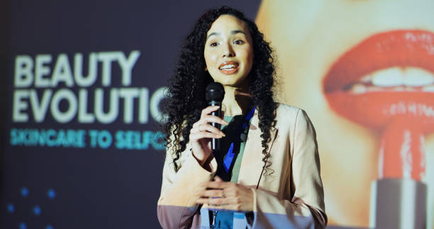 istock Woman, presentation and stage with talking at conference for beauty evolution with info for change in industry. Person, speaker and employee with mic for cosmetics company at international convention 2177819892