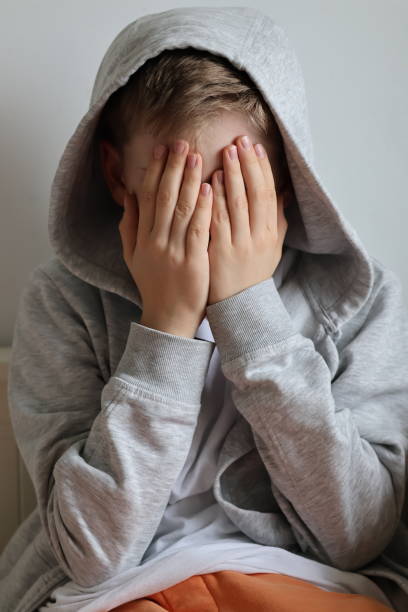 istock A sad, broken boy covering his face with his hands 2177824055