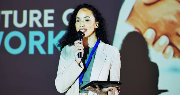 istock Stage, presenter and woman at seminar on business transformation, growth or development idea. Technology, change and speaker with mic at future of work conference with discussion, progress and tablet 2177824600
