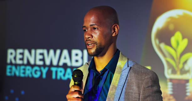 istock Talk, speaker and black man at seminar with microphone,  presentation and ideas for renewable energy. Climate change, resources and presenter at conference on sustainable power solution on screen 2177824625