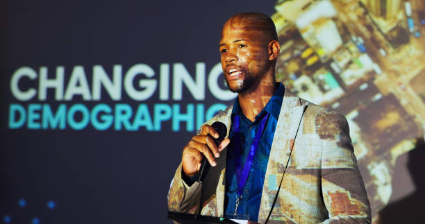 istock Presenter, conference and black man on a stage with demographics for mortality, population growth and birth rate. Public speaking, audience and person on tablet at tradeshow, convention and seminar 2177825911
