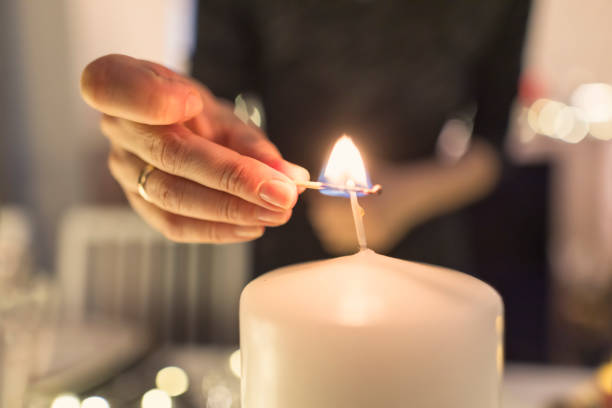 mère allumant une bougie pendant le souper de la veille de noël. - bougie allumée mur photos et images de collection