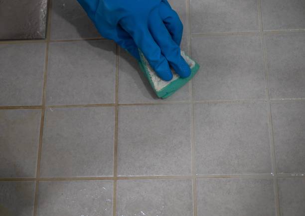 istock Tile floor was partially washed. Hand in blue gloves cleaning tile floor with sponge. 2177833171